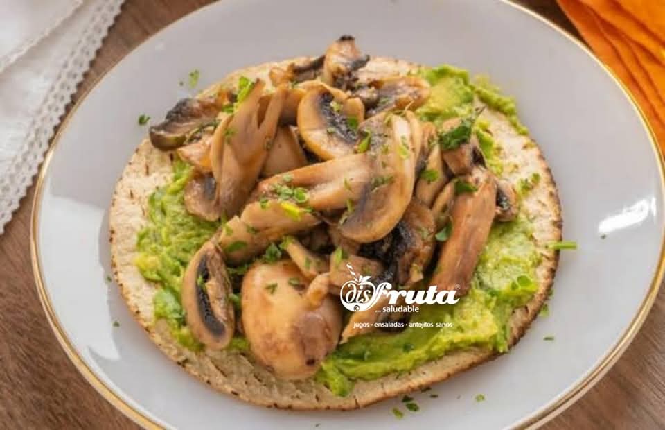 Plato con dos tostadas untadas de guacamole y champiñones